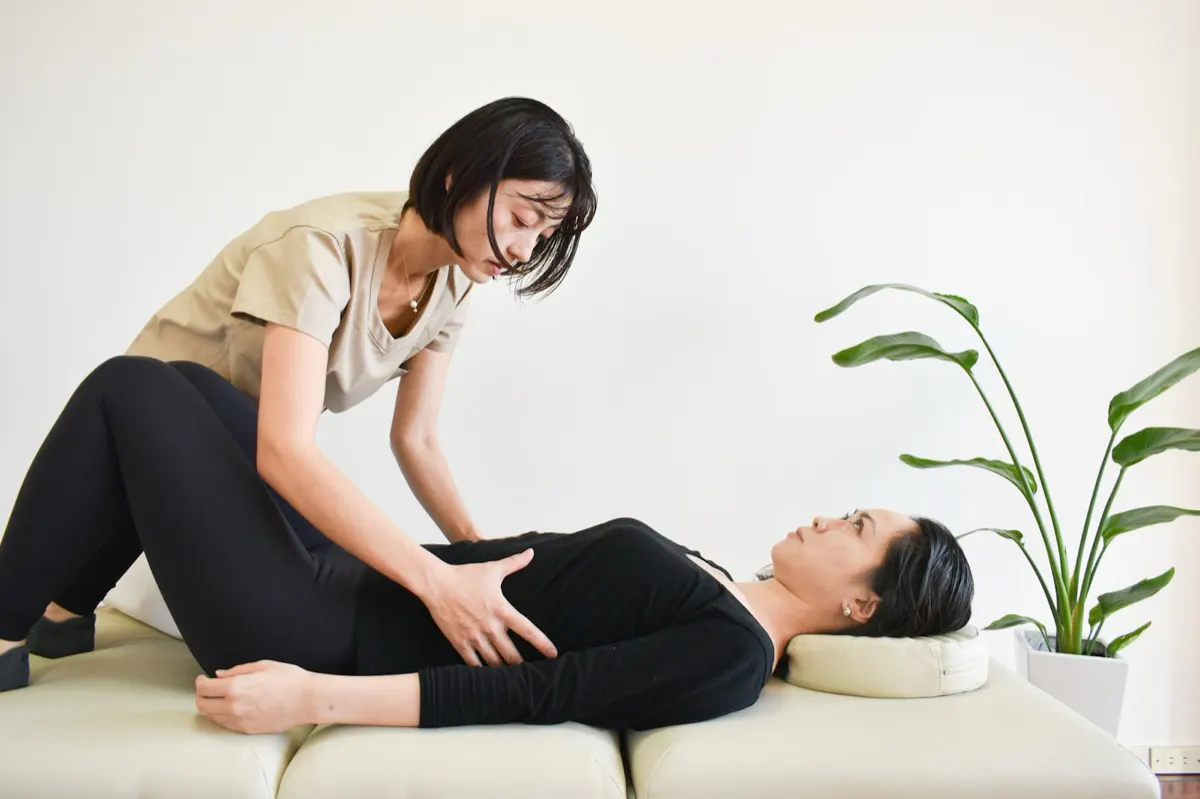 仰向けのクライアントの腹部に徒手でアプローチしている様子
